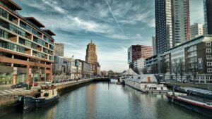 A modern city with innovative architecture, a bustling port, and cultural attractions like the Markthal and Cube Houses.